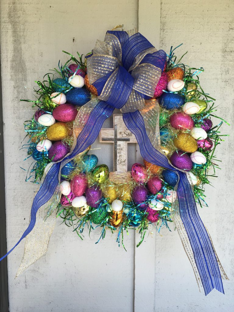 Honosný velikonoční barevný věnec zdobící vchodové dveře.